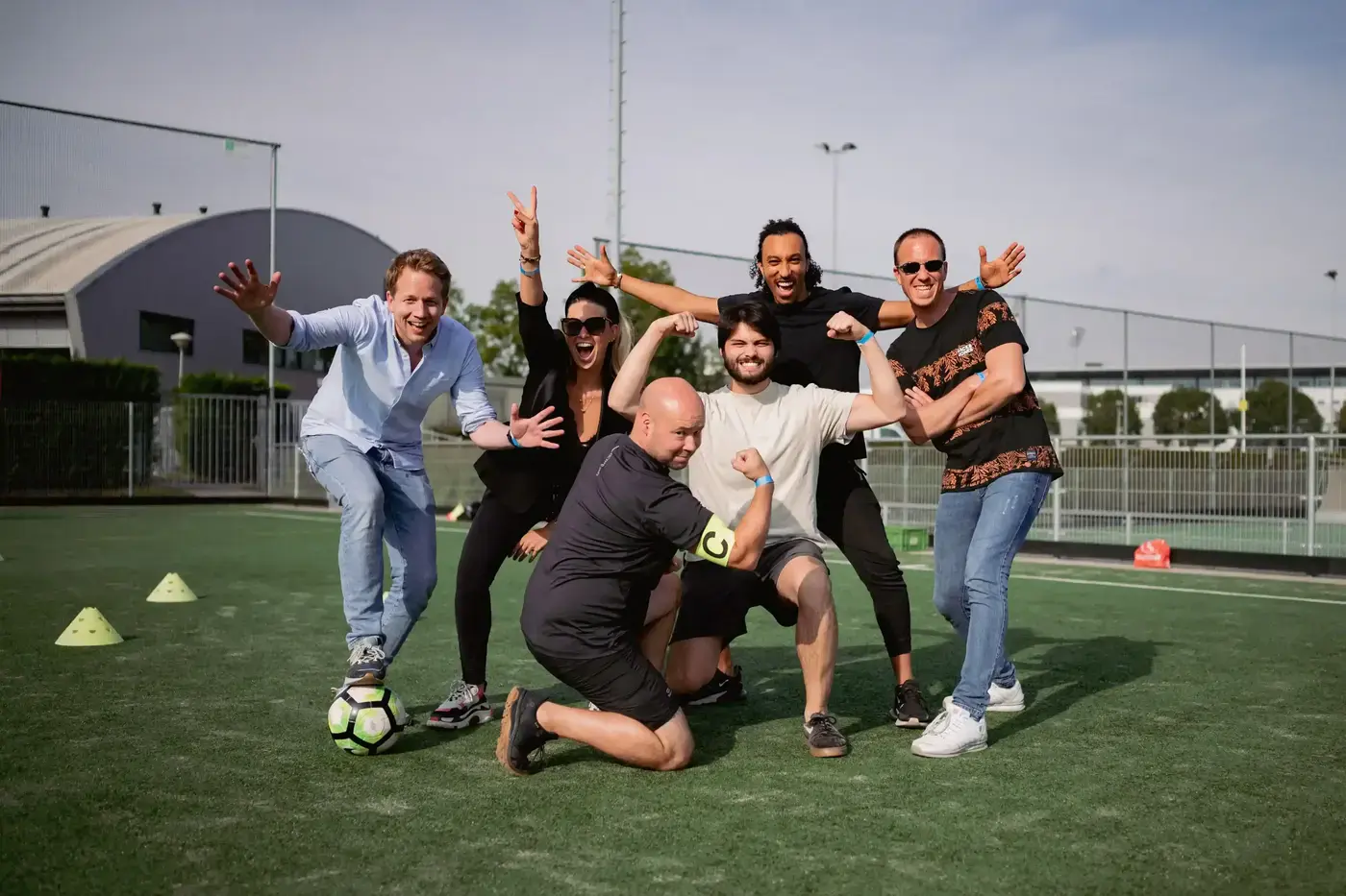 Enthousiast team poseert samen op een kunstgrasveld tijdens een actieve spellendag van WePlay United