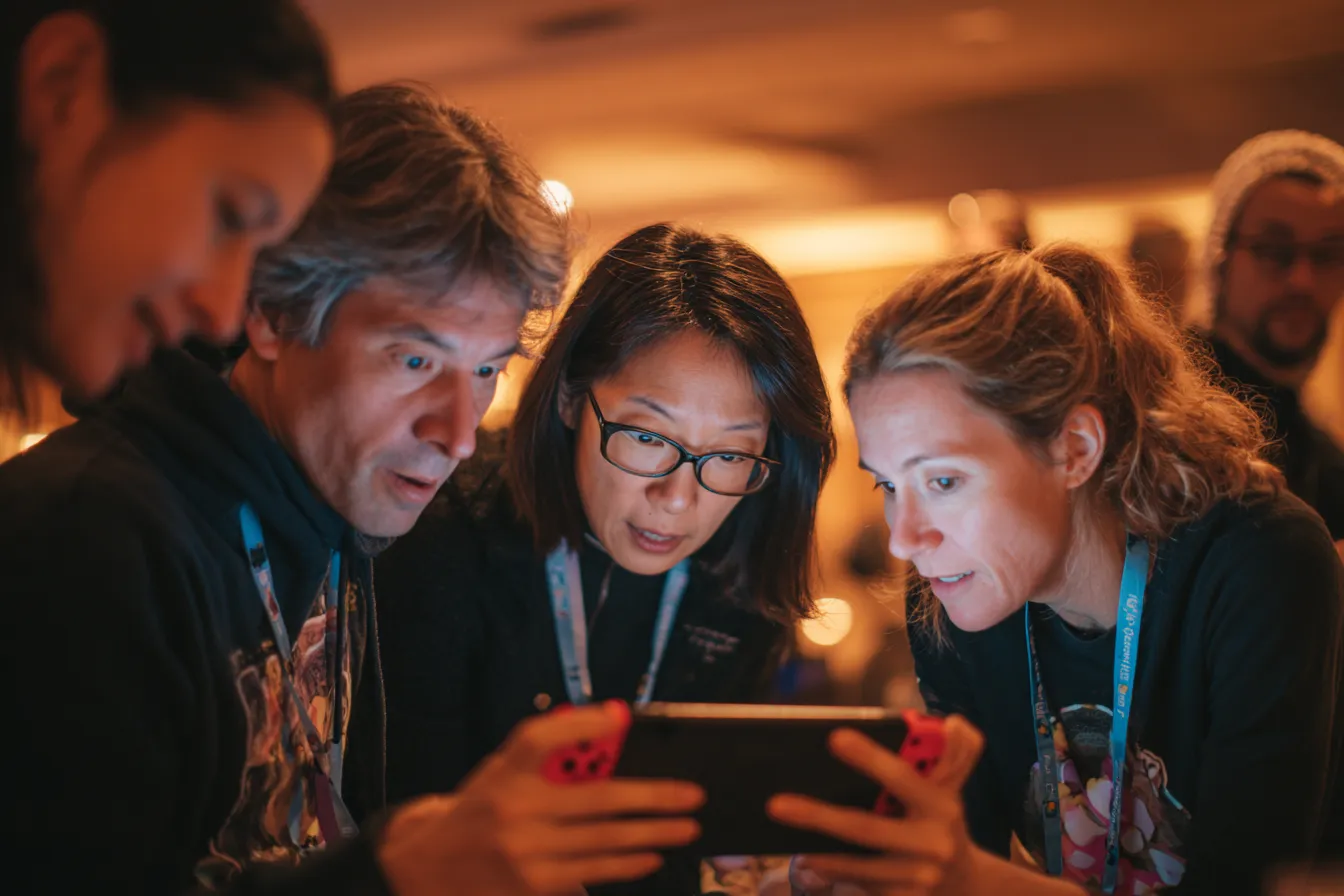 Vier volwassenen spelen intensief Bomberman op groot scherm tijdens een WePlay United event