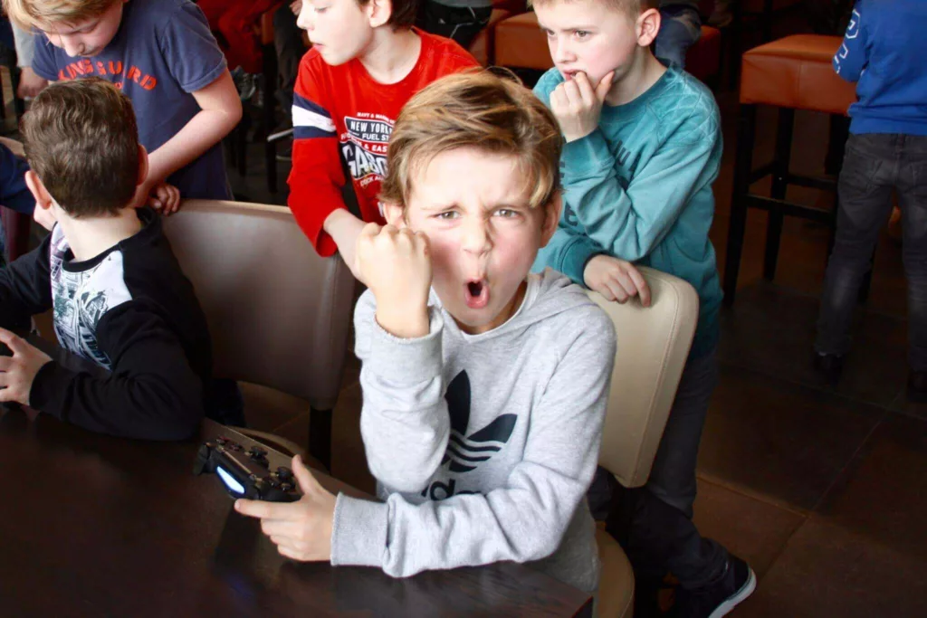 Jongen kijkt recht in de camera en juicht tijdens een FIFA toernooi