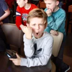 Jongen kijkt recht in de camera en juicht tijdens een FIFA toernooi