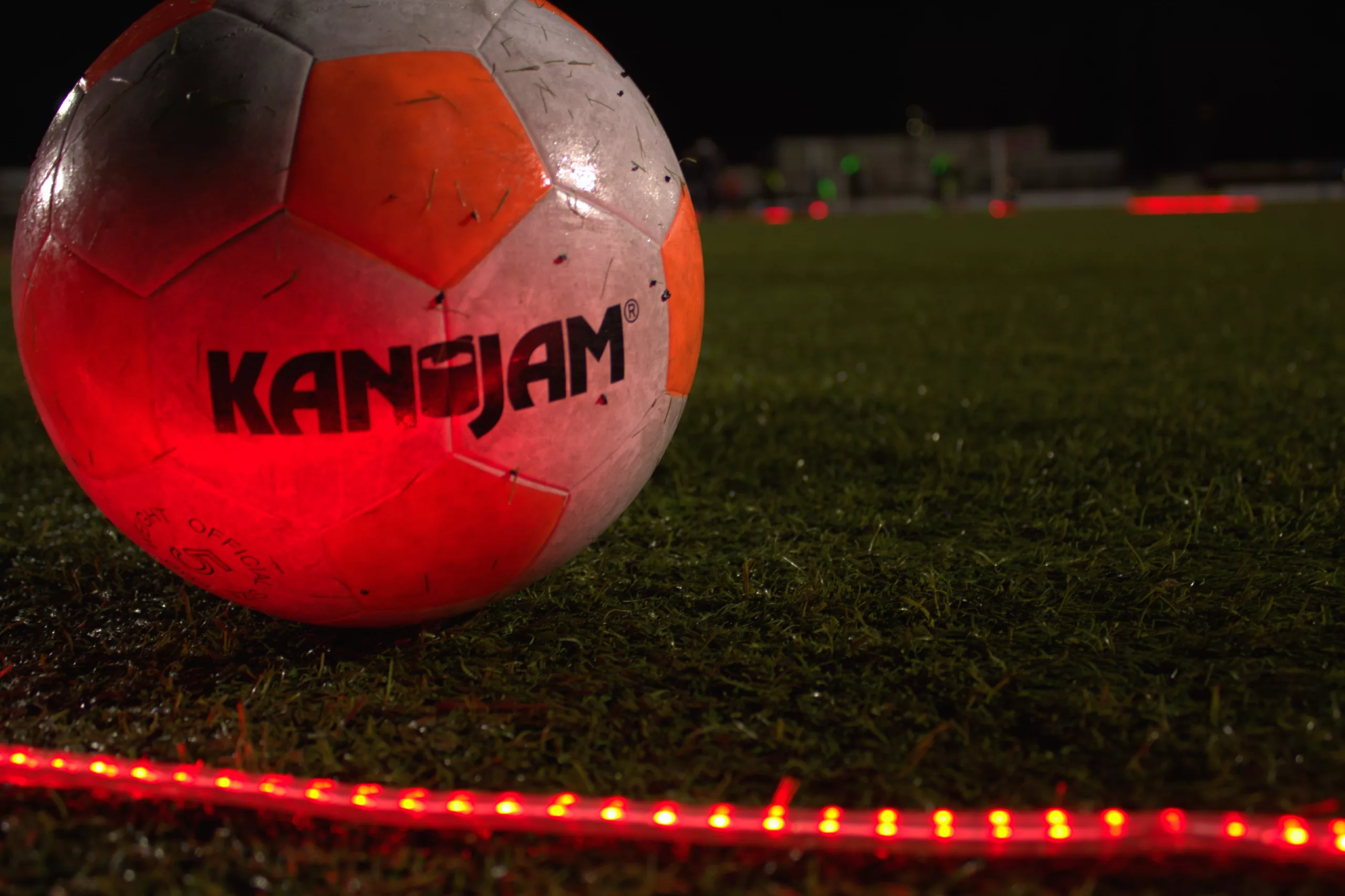 Foto van een LED voetbal bal met rode LED strips op een voetbalveld